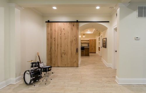 Finished basement with custom arches and an oversized wooden sliding barn door. 