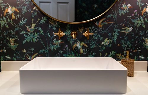 Vibrant jungle wallpaper with brass hardware and round mirror. 
