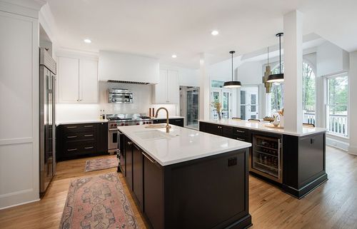 The brass hardware shines in this black and white kitchen. Double islands ensure plenty of room for meal prep and in-kitchen dining.