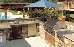 Stone patio leads to an outdoor kitchen.