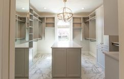 Walk-in closet with shaker cabinets and marble pattern floors.