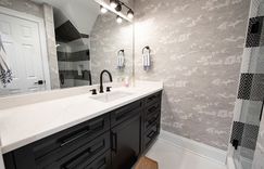 This black and white monochromatic bathroom features illustrative wallpaper and penny round tile that puts an emphasis on texture in this cozy bathroom. 